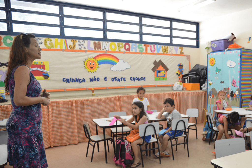 Em sala de aula, professora conversa com alunos.