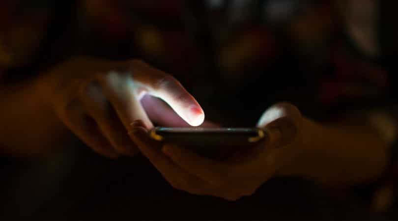 Pessoa usando celular e enviando mensagem de texto.